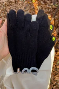 Detailed shot of black knit gloves with grey ruffle cuffs and touch screen fingertips.