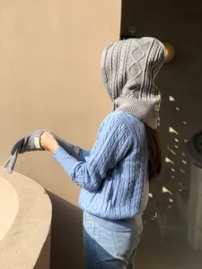 Grey knit hooded scarf detail shot, showing cable knit texture and matching gloves in use.