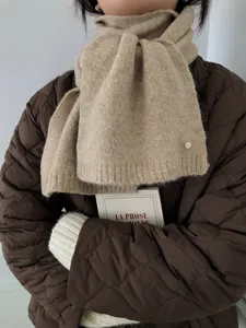 Detailansicht eines warmen Strick-Winterschals in Haferflockenfarbe, elegant getragen.