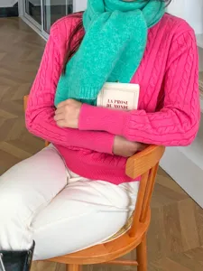 Detailaufnahme eines kuscheligen Winterschals aus Lammwolle in Unifarbe mit Pullover.