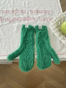 Detailansicht von kuscheligen grünen Plüschfäustlingen, weichen warmen Winterhandschuhen für Damen.