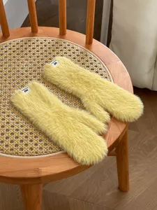 Detailaufnahme kuscheliger gelber Plüsch-Winterhandschuhe auf Stuhl, weiche warme Textur.