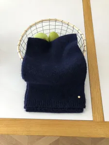 Detailaufnahme eines gemütlichen dunkelblauen Schals, ordentlich in einem Drahtkorb platziert.