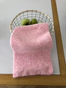 Nahaufnahme der soften pinken Strickschal Textur, dekoriert im Korb mit frischen Äpfeln.