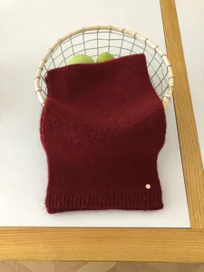 Nahaufnahme eines kuscheligen dunkelroten Winter-Wollschals im Drahtkorb, Strickdetails.