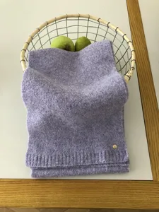 Detailansicht eines kuscheligen Lavendel-Strickschals mit weicher Textur und feinem Metallelement.