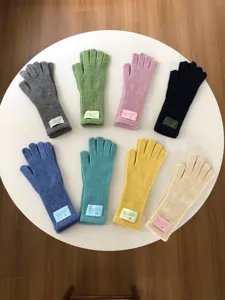 Détail de gants tactiles tricotés multicolores élégamment disposés sur une table ronde.