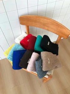 Detailaufnahme mehrfarbiger Strickschals, ordentlich gestapelt auf Holzstuhl, kuschelig.