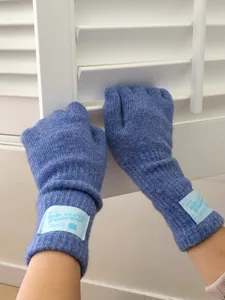 Gros plan de gants d'hiver en tricot bleu avec design à doigts séparés et étiquette de marque.
