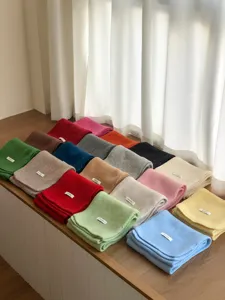 Detailed view of colorful solid wool scarves neatly folded on wooden table for winter warmth.
