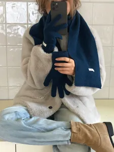 Detailed shot of a cozy dark blue knitted wool scarf and matching gloves in winter lifestyle.