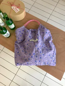 Detailaufnahme der lila blumigen Knitter-Tragetasche mit rosa Seilgriffen für Sommer.