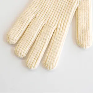 Gedetailleerde close-up van zachte beige gebreide winterhandschoenen met nette ribstructuur.