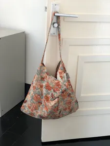 Detailed view of casual floral canvas shoulder bag hanging on door, everyday student tote.