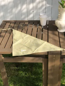 Detailansicht des karierten Dreiecktuchs mit feinem Muster auf Holztisch präsentiert.