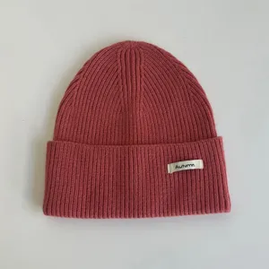 Bonnet d'hiver en tricot douillet de couleur rose brique avec petite étiquette tissée.