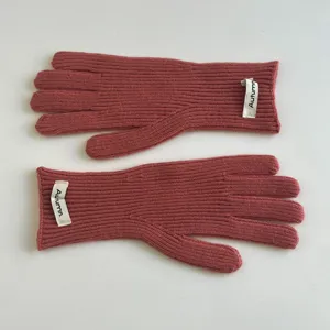 Gros plan détaillé de gants en tricot douillets rose ancien avec côtes et petite étiquette.