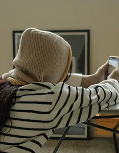 Λεπτομερής όψη μιας ζεστής πλεκτής κουκούλας μπαλακλάβα και ασορτί μανικιών σε μπεζ χρώμα.