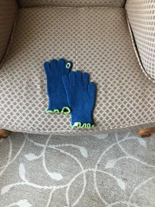 Detail view of women's warm knit touchscreen gloves in blue with green frilly cuffs.