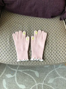 Close-up detail of pink winter knitted touchscreen gloves with cute white ruffle cuffs.