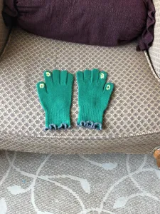 Close-up of green knit touchscreen gloves featuring cute floral fingertips and ruffled cuffs.