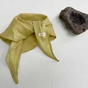 Vista dettagliata di un semplice foulard triangolare in lino tinta unita, leggero ed elegante.
