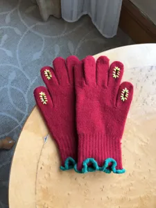 Red knitted gloves for women with green ruffle cuffs and cute yellow finger embroidery details.