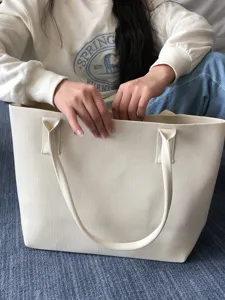 Vue détaillée d'un grand sac cabas tricoté minimaliste en blanc cassé, design élégant.