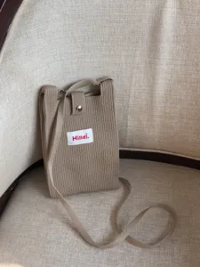 Vista detallada del elegante bolso cruzado mini de punto para teléfono con botón a presión.