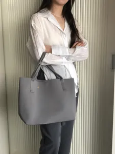 Vue détaillée du grand sac cabas gris en tricot, mettant en valeur la texture et les anses.
