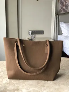 Vue détaillée du sac cabas en tricot uni montrant le tissu texturé et les bretelles résistantes.