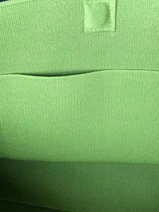 Détail intérieur du cabas en tricot vert, présentant une texture tissée et une poche.
