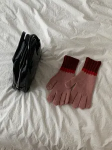 Close-up of cute colorblock knit gloves in pink and red, warm winter five-finger design.