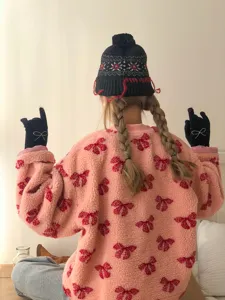 Close-up detail view of cute winter knit gloves with rhinestone bow and cozy beanie hat.