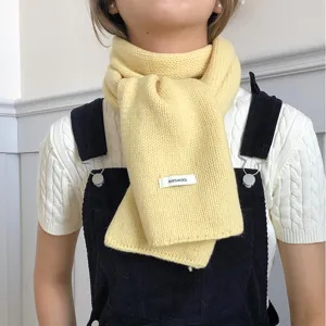 Yellow knit wool scarf detail shot, warm winter accessory showing soft texture and cozy wear style.