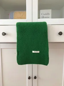 Detailed view of the green wool knitted scarf, winter warm cozy chic shawl accessory.