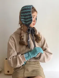 Photo de detail d'un bonnet en tricot d'hiver et de gants chauds portes, accessoire de saison.