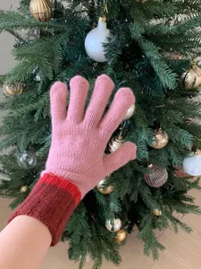 Pink knitted winter gloves detail shot, cozy wool fabric and color blocked design.
