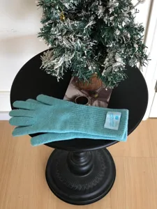 Gros plan detaille des gants d'hiver en tricot turquoise confortable avec poignets côtelés et etiquette.
