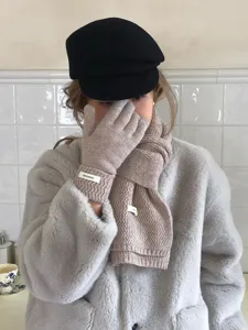 Close-up detail of the knitted wool scarf and gloves, showing cozy winter warmth.