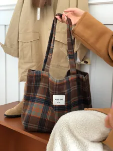 Woolen plaid tote bag detail showing large capacity, cozy shoulder strap and soft winter fabric.