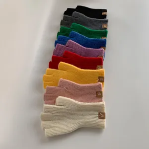 Nahaufnahme von bunten Strick-Fingerlos-Handschuhen ordentlich auf weißer Oberfläche.