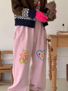 Detailed view of winter fashion apparel, cute pink sweatpants with bear prints and warm gloves.