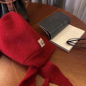 Primo piano di una comoda sciarpa con cappuccio balaclava in maglia rossa su tavolo di legno.
