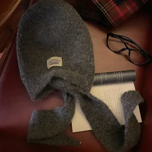 Dettaglio passamontagna in maglia di lana grigio scuro, sciarpa integrata, accessorio invernale.