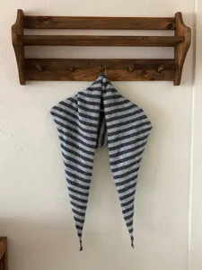 Vista detallada del elegante pañuelo triangular de punto a rayas, con textura y forma única.