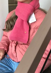 Toma detallada de una elegante bufanda rosa de punto con textura suave y detalle chic.