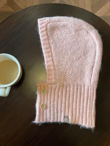Detalle de pasamontañas de punto rosa, capucha de invierno suave y cálida con botones.