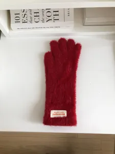 Detailed view of cozy red winter plush gloves on white surface, showing soft fuzzy texture.
