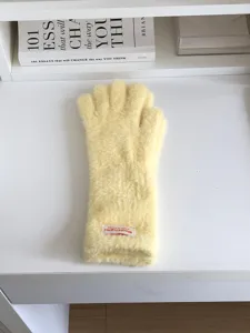Close-up detail of fluffy yellow winter gloves, soft warm plush knit for cold weather wear.